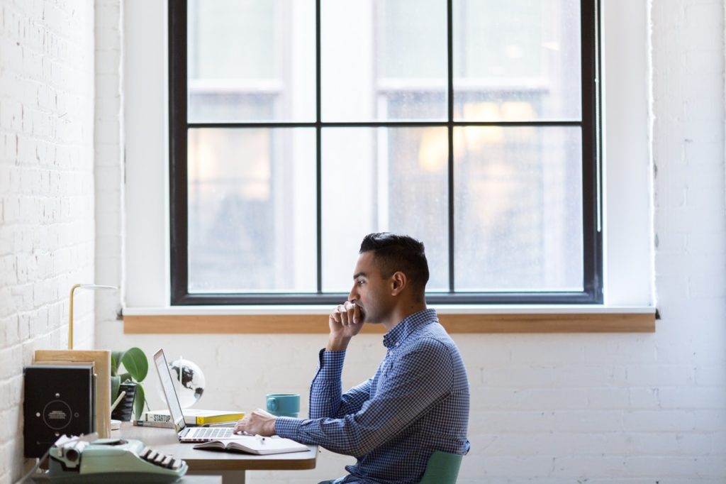 Homem trabalhando em home office na frente de janela